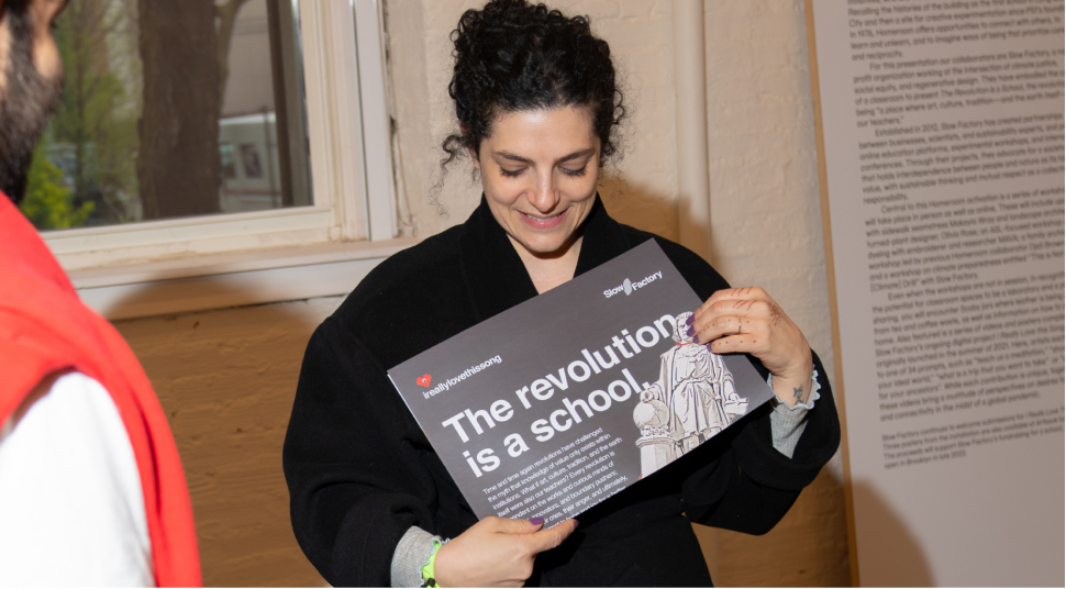 Céline Semaan holding up a page that reads, “The Revolution is a school.”