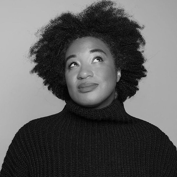 Aja Barber, A black and white image of a Black woman with short curly hair, wearing a black turtleneck.