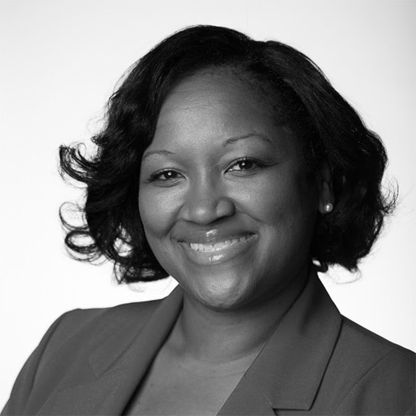 Tracie McLee, a Black woman with wavy hair in a blazer, smiling